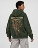 Model wearing the green skeleton flower hoodie with stone trousers, back three-quarter view