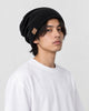 Model wearing the black slouch beanie low over the ears with a white tee, three-quarter view