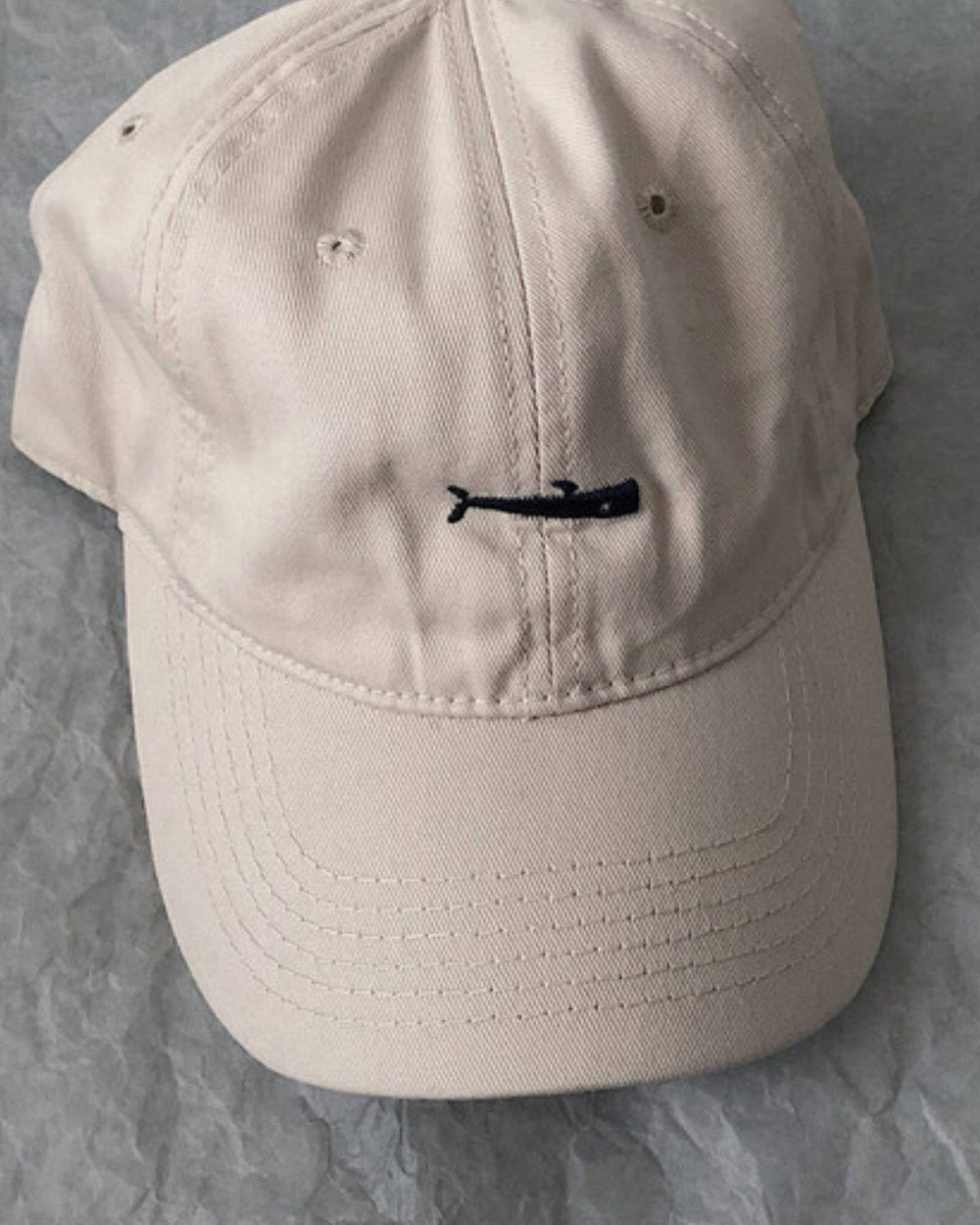 Close-up of the small black whale embroidered on the beige cap
