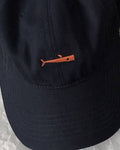 Close-up of the small orange whale embroidered on the navy cap