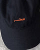Close-up of the small orange whale embroidered on the navy cap