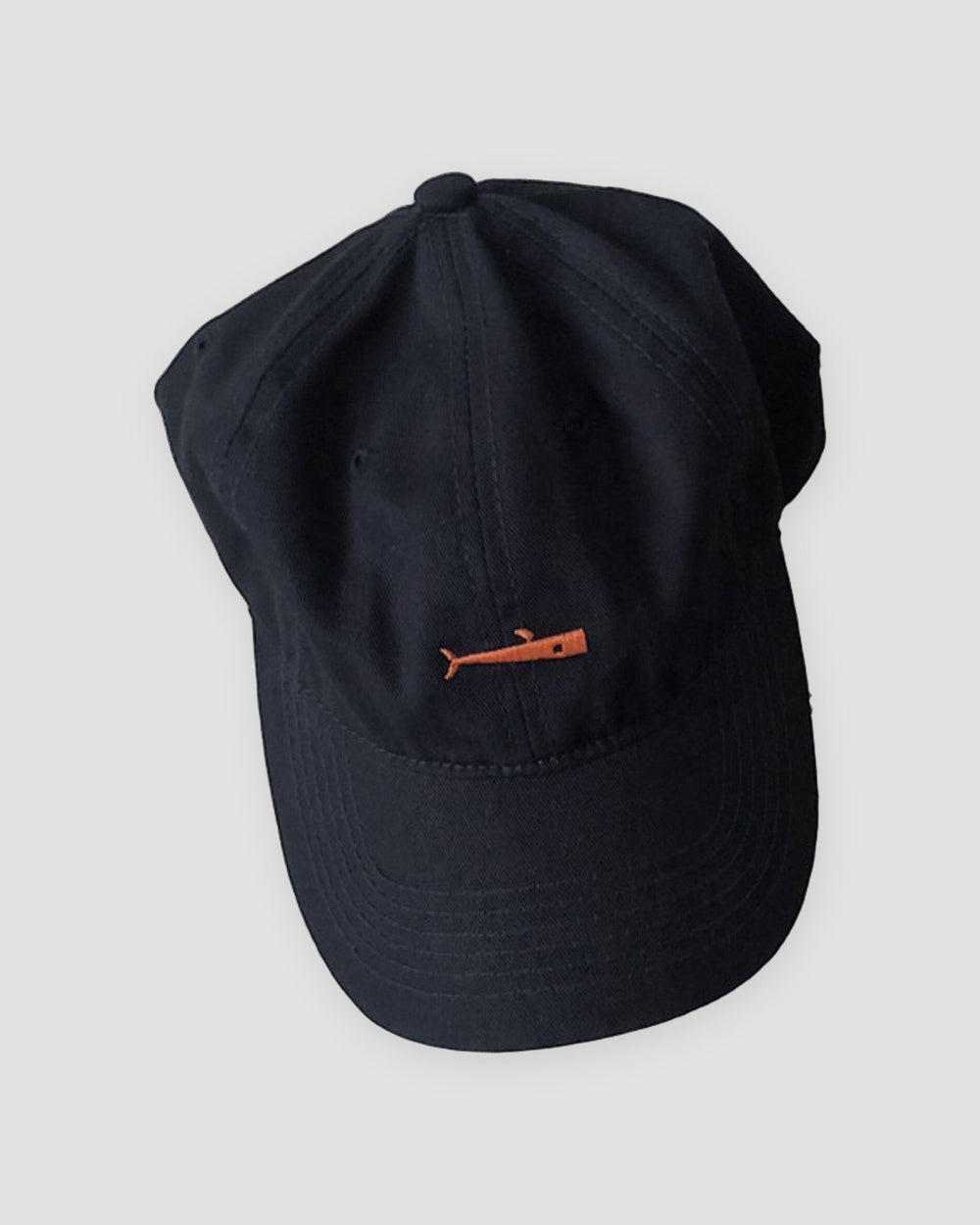 Navy baseball cap with a small orange whale embroidered at the front center
