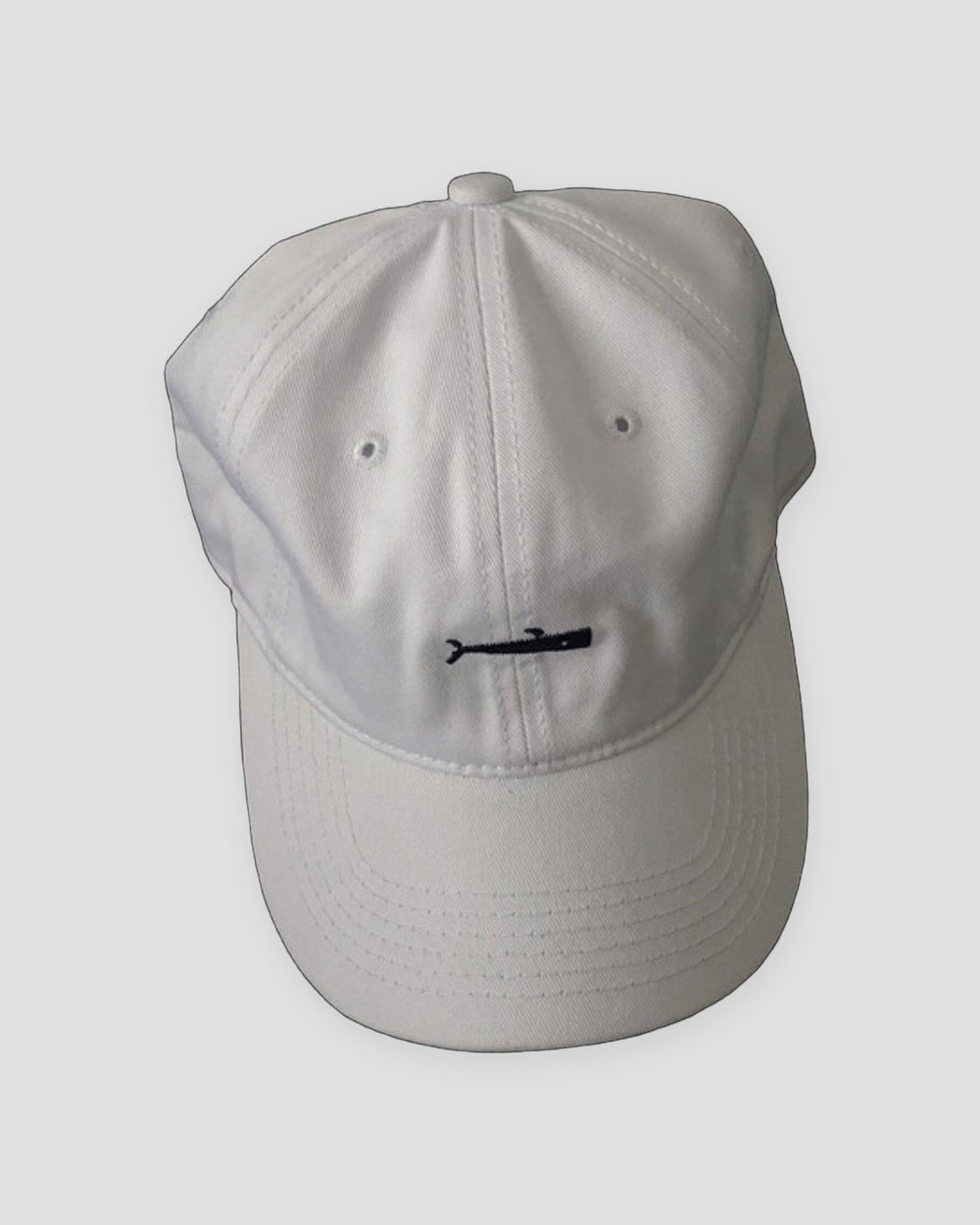 White baseball cap with a small black whale embroidered at the front center
