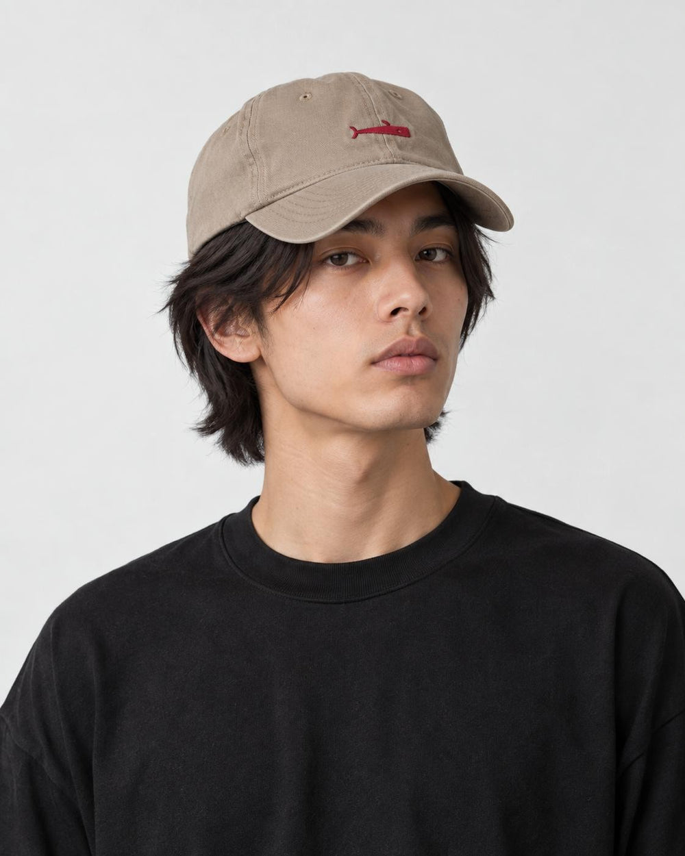 Model wearing the khaki whale cap with a black tee, three-quarter view