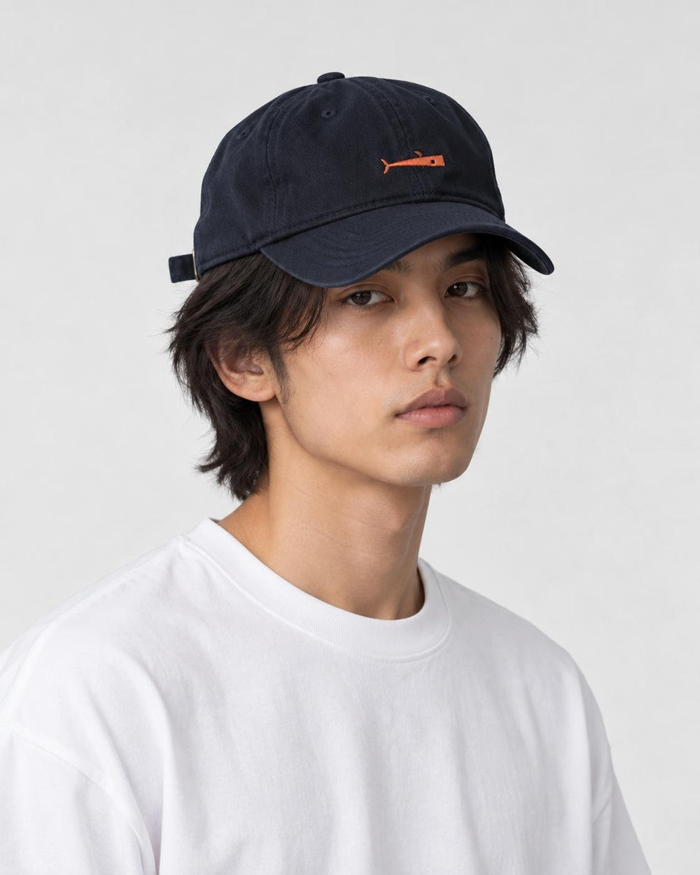 Model wearing the navy whale cap with a white tee, three-quarter view