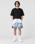 Model wearing the snowy mountain print shorts with a black T-shirt, front view
