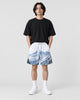 Model wearing the snowy mountain print shorts with a black T-shirt, front view