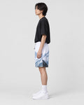 Model wearing the snowy mountain print shorts with a black T-shirt, side view