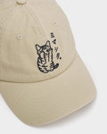 Close-up of the black embroidered cat with its paw over its face and the katakana on the cream cap