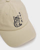 Close-up of the black embroidered cat with its paw over its face and the katakana on the cream cap
