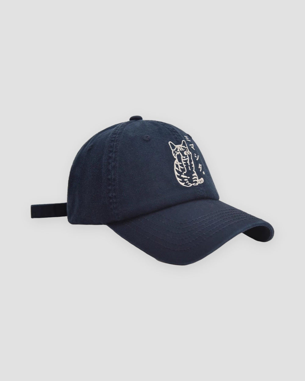 Navy baseball cap with a white embroidered seated cat and katakana, three-quarter view