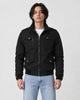 Model wearing the black field jacket zipped over a white tee and light-wash jeans, front view