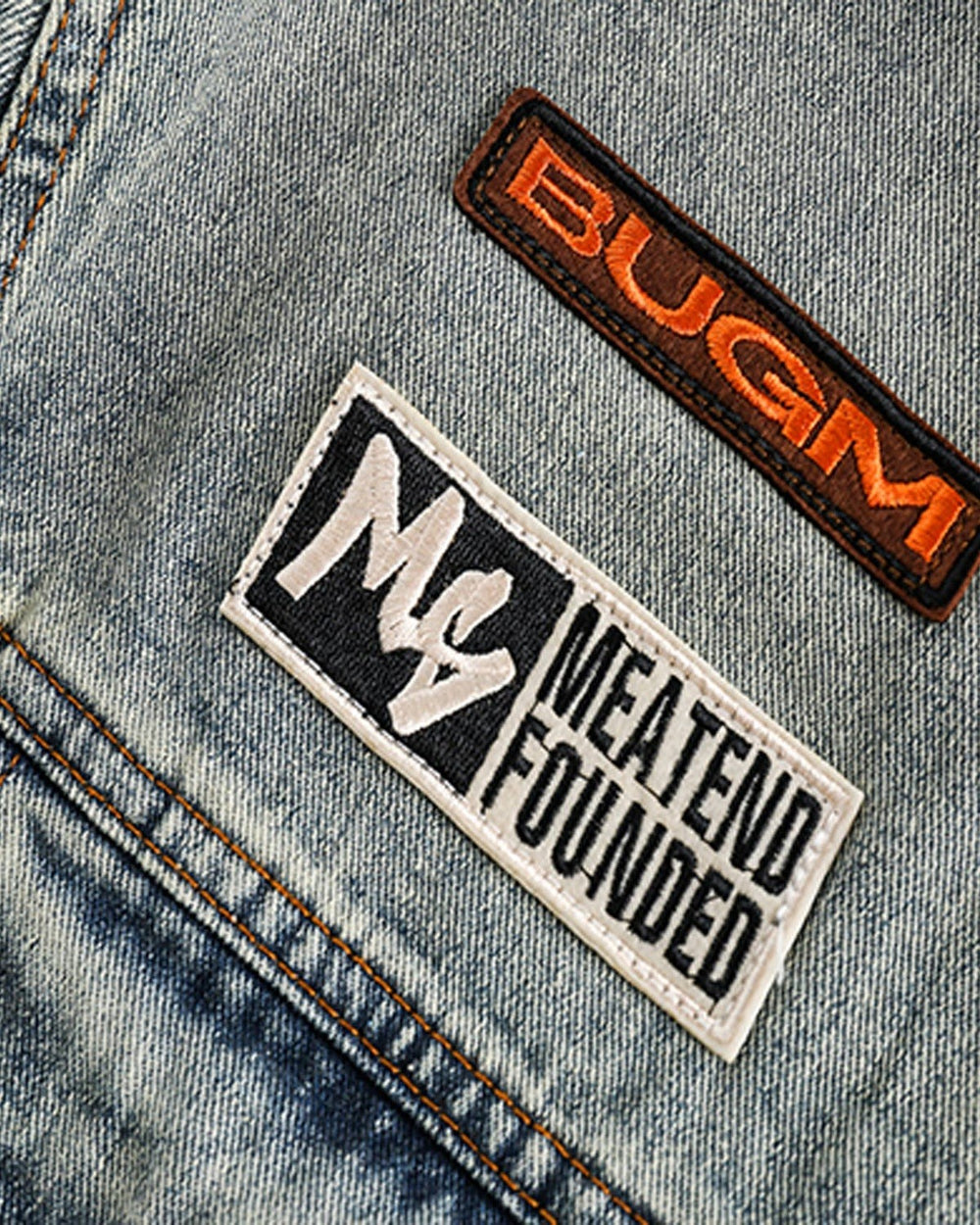 Close-up of the orange BUGM label and MEATEND FOUNDED patch on the chest