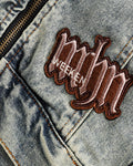 Close-up of the raised maroon script patch on the front