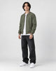 Model wearing the army green striped bomber jacket, three-quarter view
