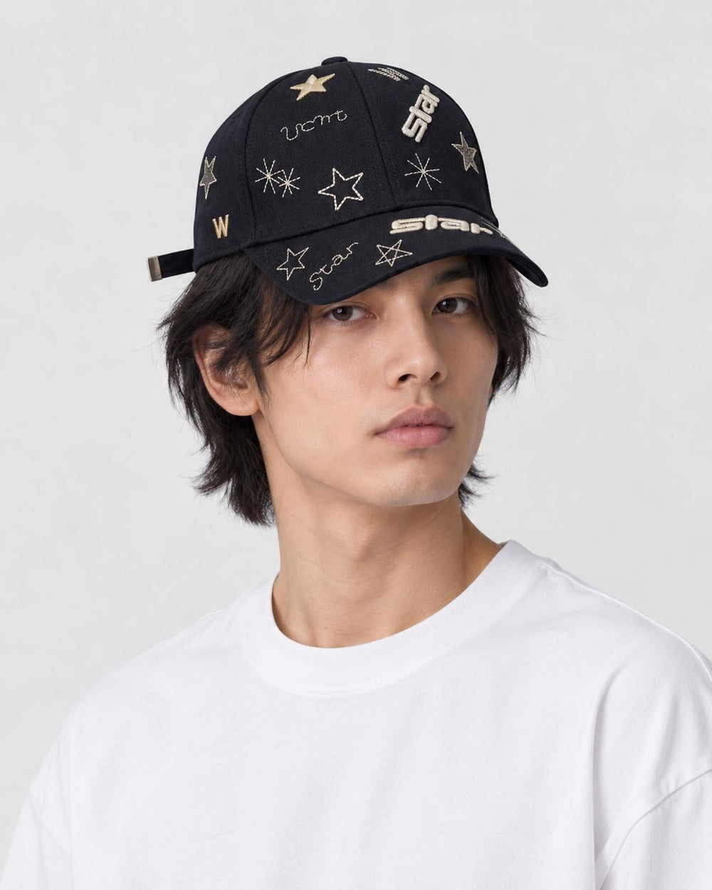 Man wearing the black baseball cap with gold embroidered stars and the word star, three-quarter view
