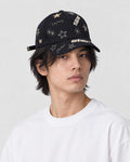 Man wearing the black baseball cap with gold embroidered stars and the word star, three-quarter view