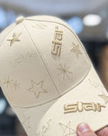 Cream baseball cap held in a hand, with tone-on-tone star embroidery on the crown and brim