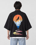 Man seen from behind in the black haori with an orange sun, a soaring bird and a winding river on the back, over a white tee