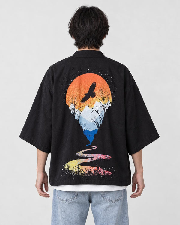 Man seen from behind in the black haori with an orange sun, a soaring bird and a winding river on the back, over a white tee