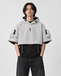 Model wearing the light gray cropped hooded poncho top over a black tee, front view