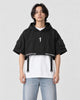 Model wearing the black cropped poncho top over a white tee, front view
