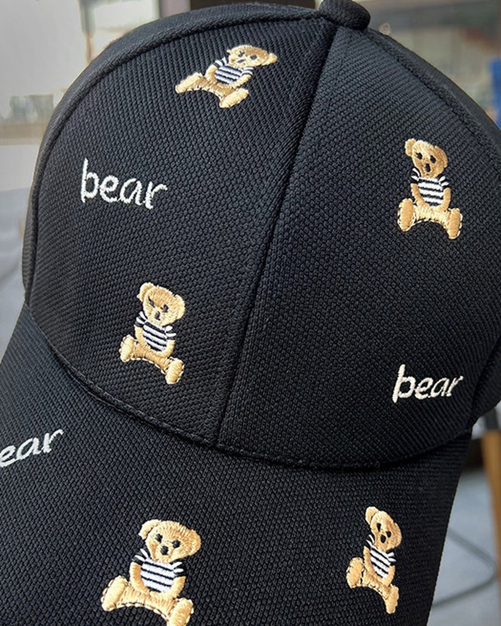 Close-up of the tan teddy bears and white bear lettering embroidered on the black cap