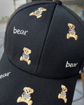 Close-up of the tan teddy bears and white bear lettering embroidered on the black cap