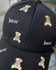 Close-up of the tan teddy bears and white bear lettering embroidered on the black cap