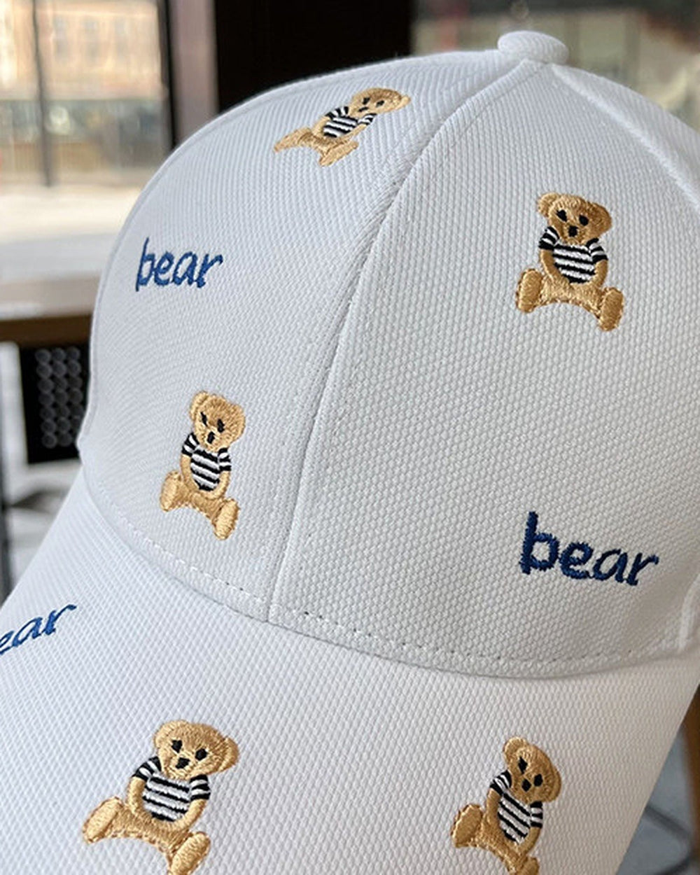 Close-up of the tan teddy bears and navy bear lettering embroidered on the white cap