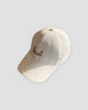 White textured baseball cap with gold-tan cursive best embroidery on the front and a curved brim