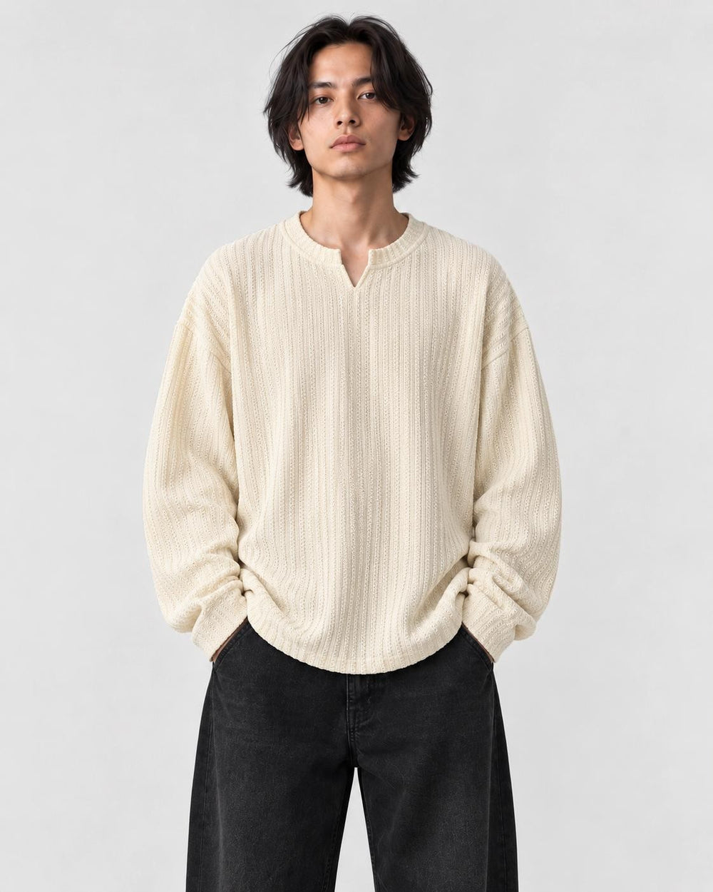 Model wearing the cream textured V-neck long sleeve tee with black trousers, front view