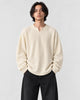 Model wearing the cream textured V-neck long sleeve tee with black trousers, front view