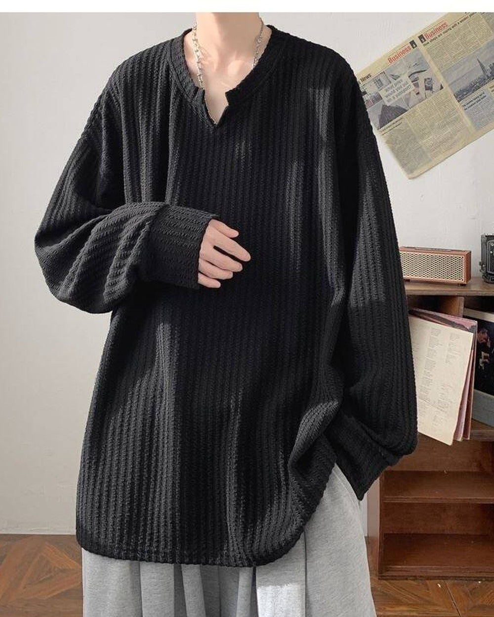Black ribbed long sleeve tee with a notched V neckline, worn with gray trousers