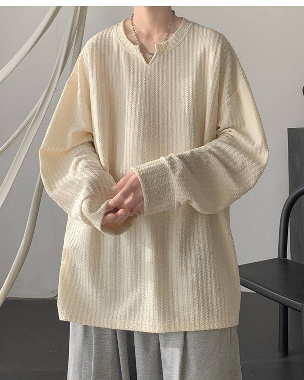 Cream ribbed long sleeve tee with a notched V neckline, worn with gray trousers