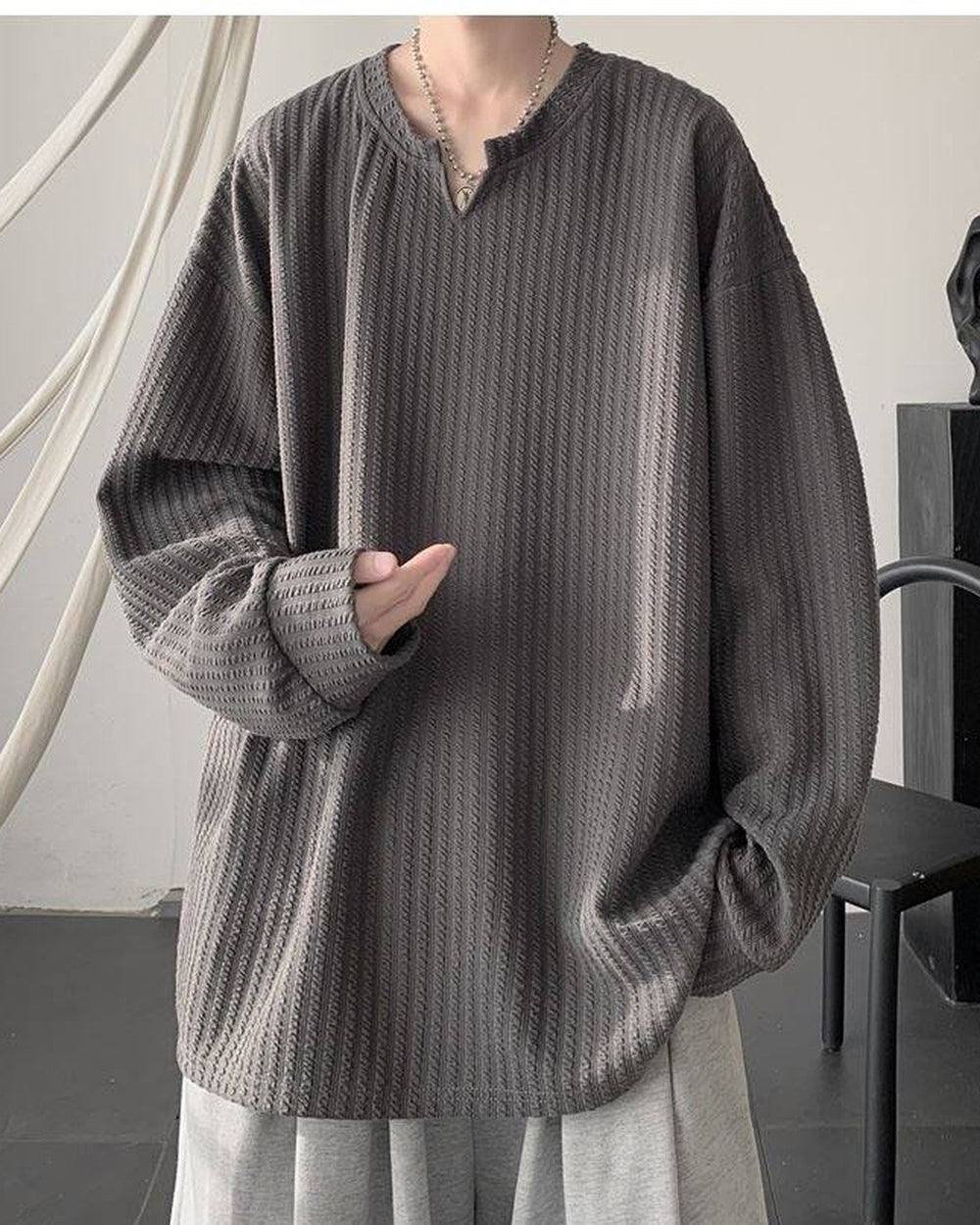 Dark gray ribbed long sleeve tee with a notched V neckline, worn with gray trousers