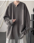 Dark gray ribbed long sleeve tee with a notched V neckline, worn with gray trousers