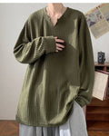 Army green ribbed long sleeve tee with a notched V neckline, worn with gray trousers