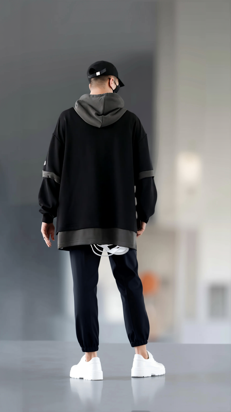 Person wearing a black outfit with a gray hood in an indoor setting