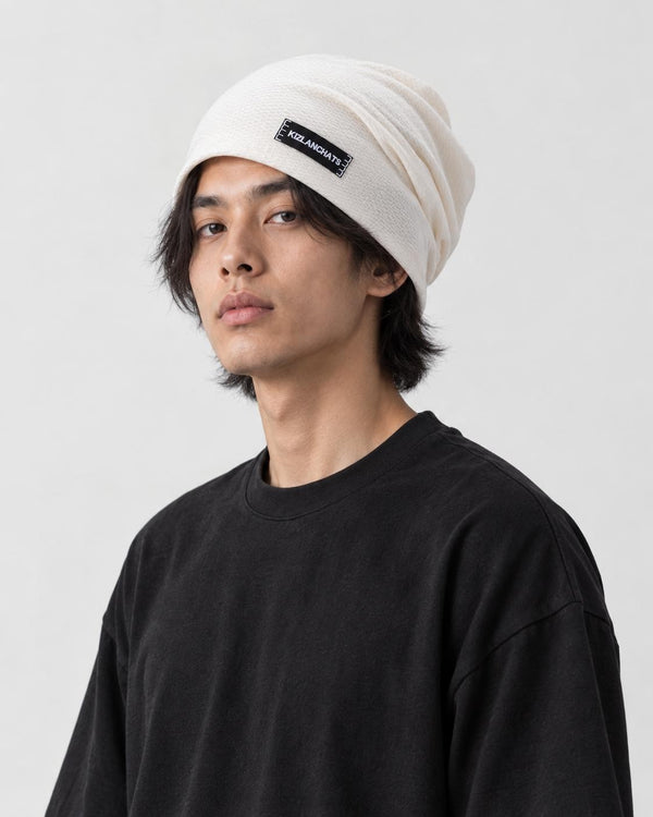 Man wearing the white slouchy beanie with a small black woven label, three-quarter view
