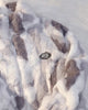 Close-up of the gray tie-dye plush pile, the white zip and the small oval patch on the chest