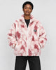 Model wearing the pink tie-dye plush zip jacket over a black tee and black jeans, front view