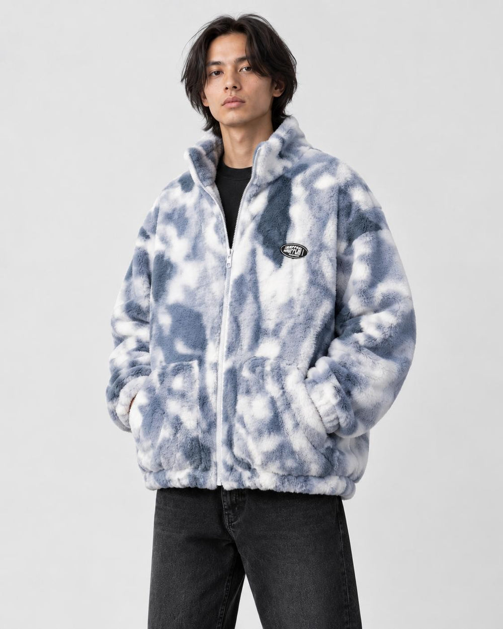 Model wearing the blue tie-dye plush zip jacket over a black tee and black jeans, three-quarter view