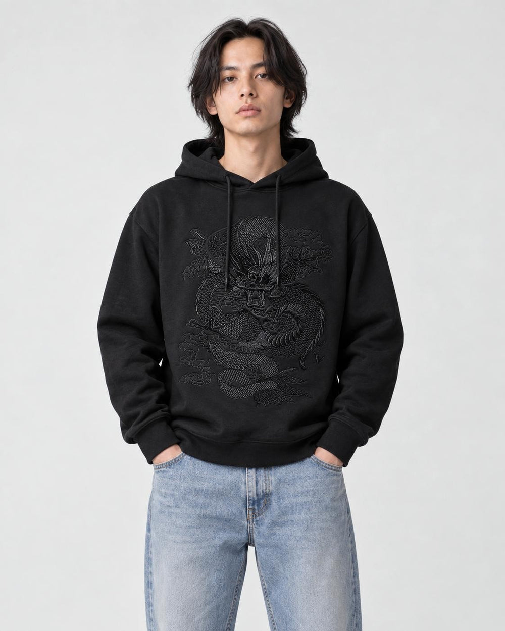 Model wearing the black dragon embroidered hoodie with light-wash jeans, front view
