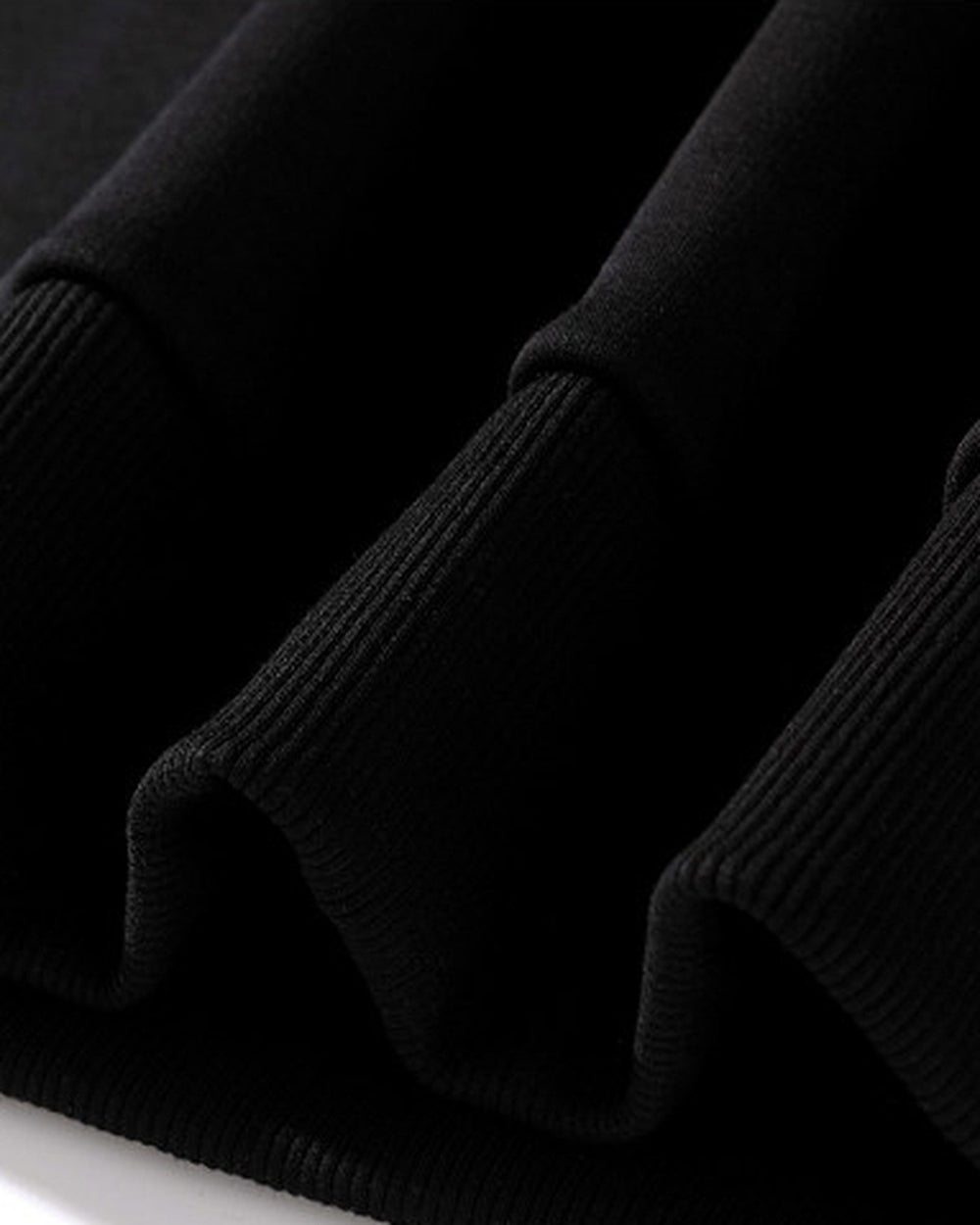 Close-up of the ribbed cuffs and hem of the black sweatshirt