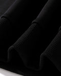 Close-up of the ribbed cuffs and hem of the black sweatshirt