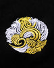 Close-up of the round white and gold swirl emblem embroidered on the chest