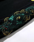 Close-up of the teal-green dragon and gold cloud scrolls embroidered down the sleeve