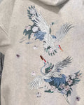 Close-up of the two embroidered cranes on the back of the oatmeal hoodie