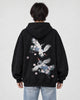 Model wearing the black crane embroidered hoodie with light-wash jeans, back view